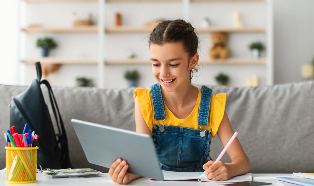 girl-sitting-at-table-using-digital-tablet-writi-2025-03-18-17-57-04-utc-min A young girl doing her home work with her online tutor for ATTC Education.
