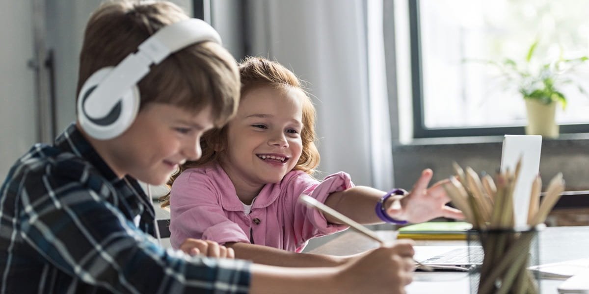 Two young kids having an online lesson at home