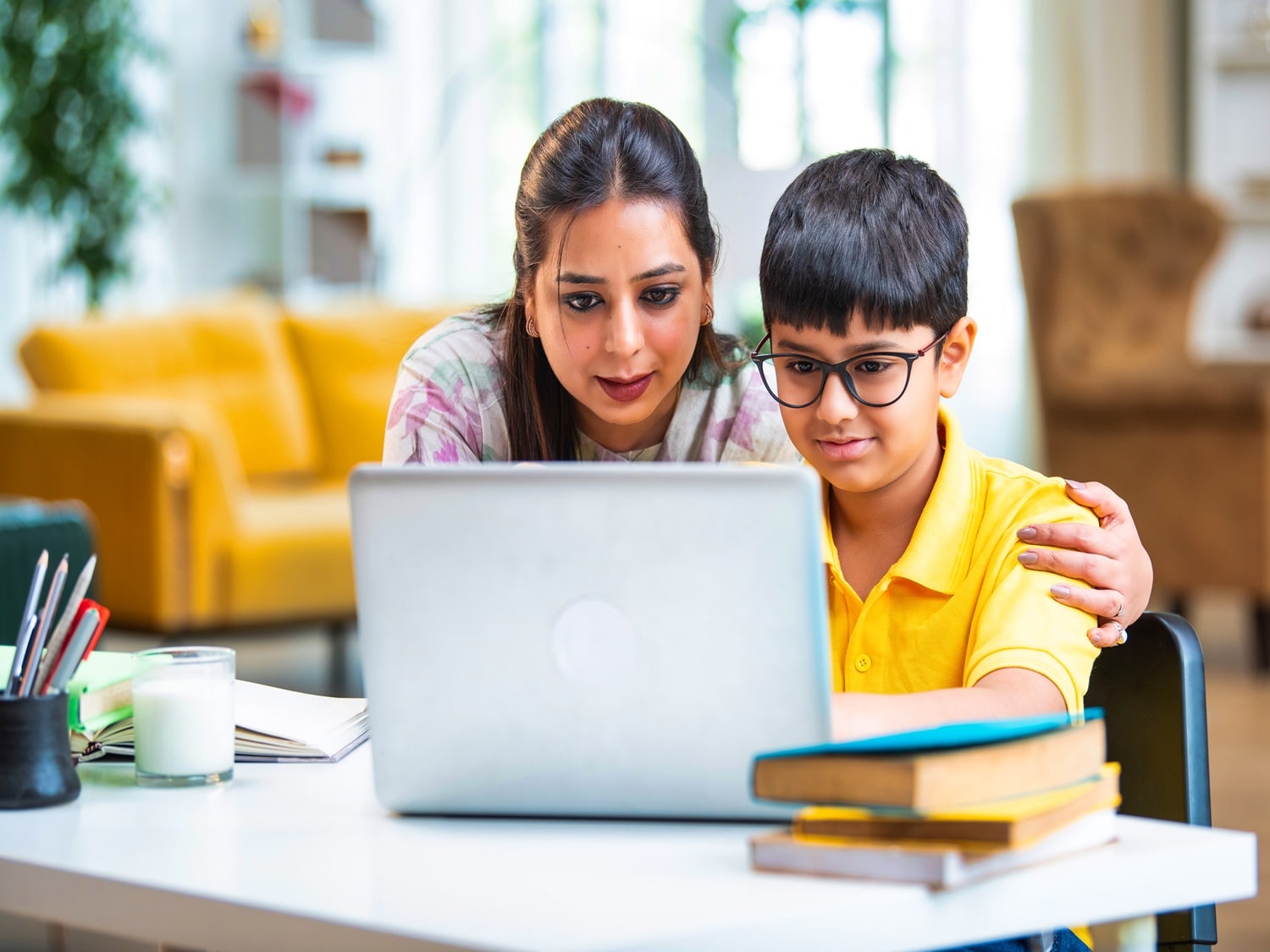 A mum sat with her child in front of her laptop, online tutor scenario.