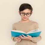 A young boy engrossed in his book, lost in the world of stories and imagination. His glasses reflect a curiosity that goes beyond the pages, highlighting the importance of reading in nurturing young minds.