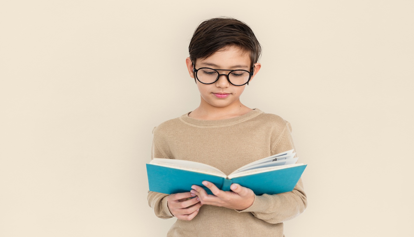 A young boy engrossed in his book, lost in the world of stories and imagination. His glasses reflect a curiosity that goes beyond the pages, highlighting the importance of reading in nurturing young minds.