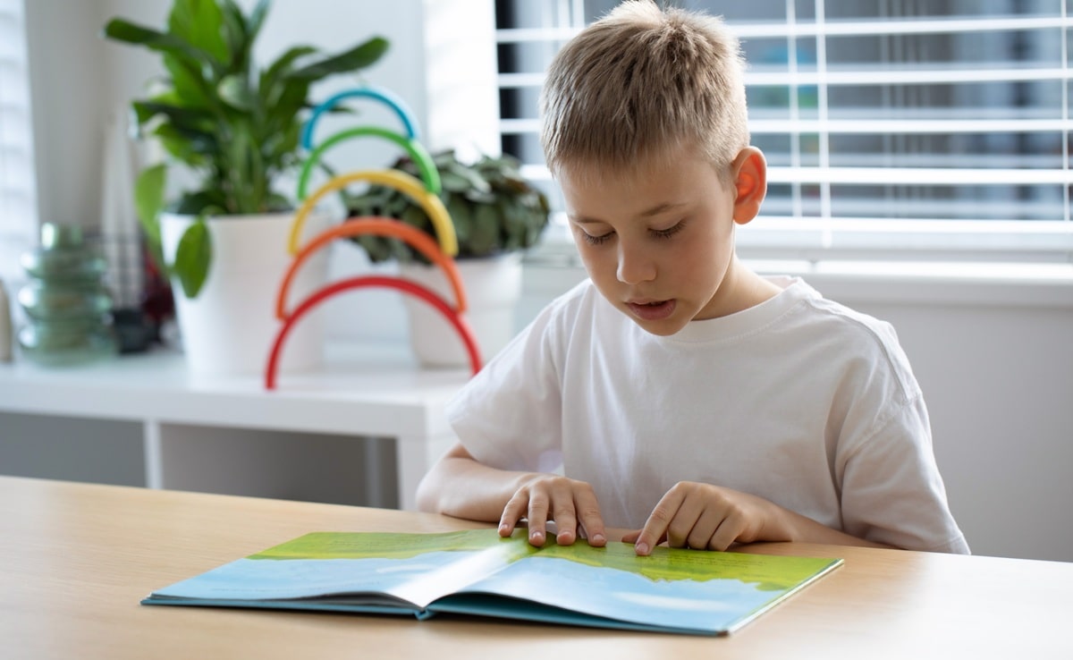 A boy reading a book at the dinning room table.