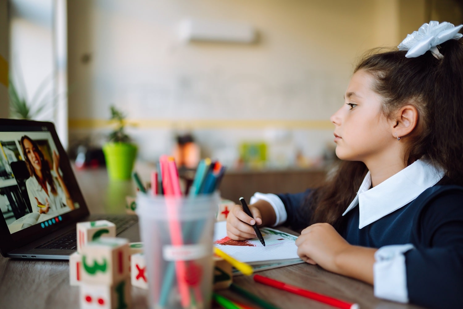 A young girl homeschooling in front of her laptop.