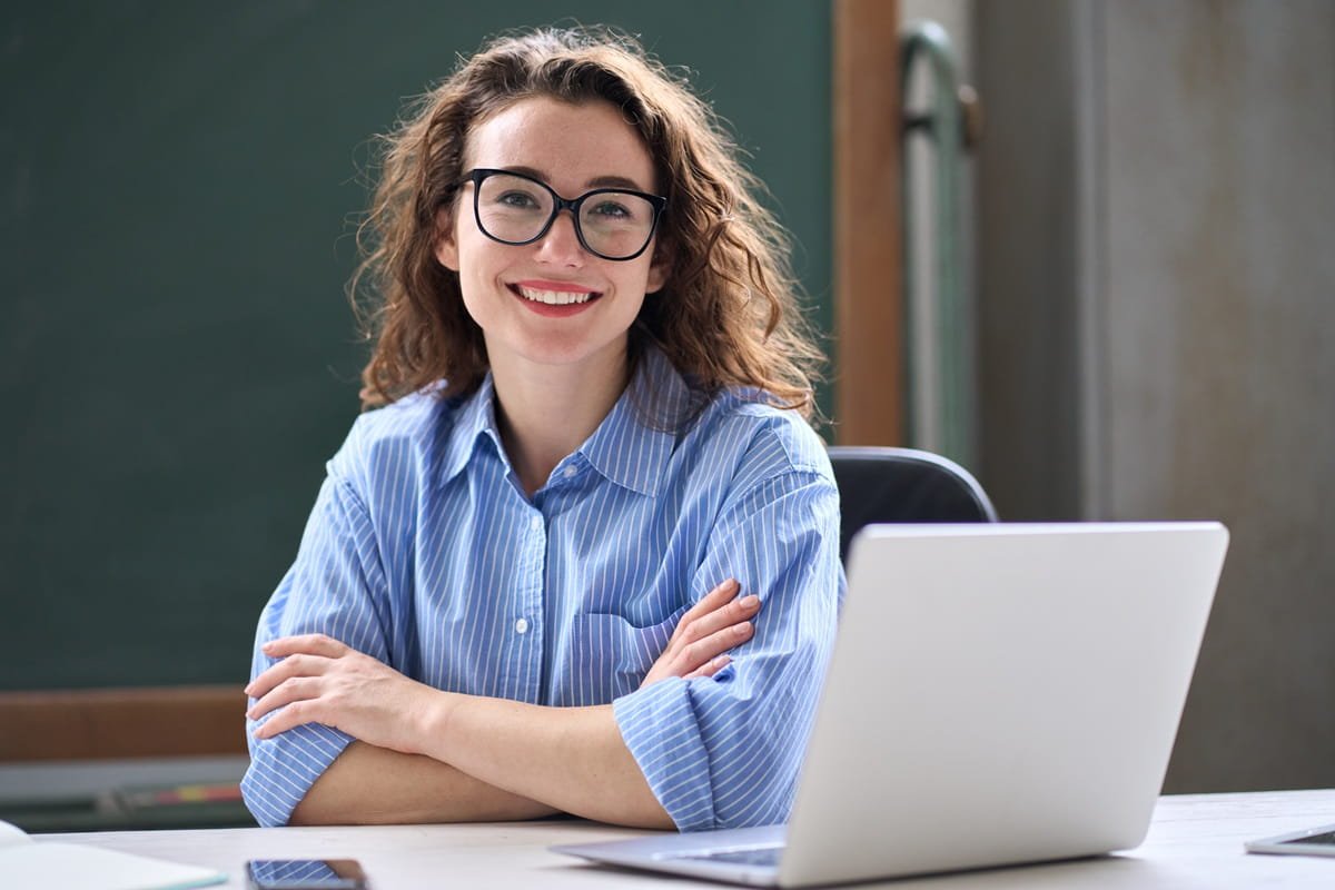 A young business lady sat with her laptop in front of her and smiling for the camera.